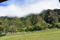 Green Mountain range with clouds rolling over it and a white fence at the base Royalty Free Stock Photo