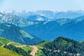 Green mountain ridges, surrounded by high mountains. Snow-capped mountain peaks on the horizon. Dirt road on mountain range. Royalty Free Stock Photo