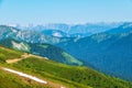 Green mountain ridges, surrounded by high mountains. Snow-capped mountain peaks on the horizon. Dirt road on mountain range. Royalty Free Stock Photo