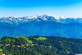 Green mountain ridges, surrounded by high mountains. Snow-capped mountain peaks on the horizon. Dirt road on mountain range. Royalty Free Stock Photo