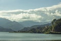 A green mountain valley under a blue sky with white clouds and houses against a lake Royalty Free Stock Photo