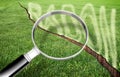 A green mowed lawn with a diagonal crack with radon gas escaping - concept with magnifying glass