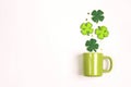 Green mug with four-leaf clover on white background. Copy space, top view Royalty Free Stock Photo