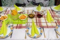 Green napkins arranged on plates in the shape of a triangle, lemonade made of water and orange slices in a large jug, salads visib