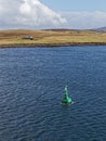 A Green Navigation Buoy with a solar Panel in the Shetland Sound on a clear Winters day Royalty Free Stock Photo