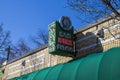 A green neon sign outside of The Euclid Avenue Yacht Club with a green awning and bare winter trees with a gorgeous clear blue sky