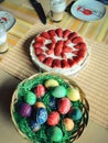 Green nest with colorful eastereggs and a strawberries cake on a