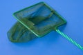 Green net for catching fish from the aquarium, blue background, mesh with a small cell Royalty Free Stock Photo