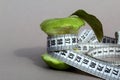 A green nibbled apple is entwined with a centimeter tape. The topic of weight loss and diet. Royalty Free Stock Photo