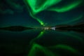 Green Northern lights reflecting in the lake with mountains and city in the background, Nuuk, Greenland Royalty Free Stock Photo
