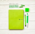 Green notebook with eraser, pen,pencil and paper clips on white wooden background. creative set for dreawing,writing or making not Royalty Free Stock Photo