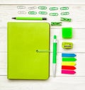 Fresh green stationary. green notebook with eraser, pen,pencil and paper clips on white wooden background Royalty Free Stock Photo