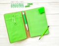 Green notebook with eraser, pen,pencil and paper clips on white wooden background Royalty Free Stock Photo