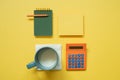 Green notepad, memo paper, color pencil, cup of milk, calculator isolated on yellow background. flat lay, top view, copy space Royalty Free Stock Photo