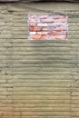 Green and ochre painted old brick wall with a patch of new brick Royalty Free Stock Photo