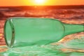 Green old bottle discarded and washed up on shore depicting environmental hazard Royalty Free Stock Photo