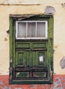 Green old shabby window in a decaying house with weathered wood