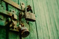The green old wooden gate is closed with a rusty latch and a metal padlock. Old architectural details Royalty Free Stock Photo