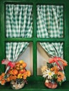 a green, old, wooden window, decorated with flowers and a checkered green-and-white curtain