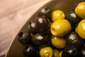 Green olives and black olives in a ceramic bowl on a wooden background. Close up Royalty Free Stock Photo