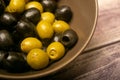 Green olives and black olives in a ceramic bowl on a wooden background. Close up Royalty Free Stock Photo