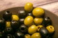 Green olives and black olives in a ceramic bowl on a wooden background. Close up Royalty Free Stock Photo