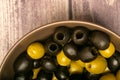 Green olives and black olives in a ceramic bowl on a wooden background. Close up Royalty Free Stock Photo