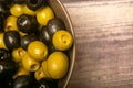 Green olives and black olives in a ceramic bowl on a wooden background. Close up Royalty Free Stock Photo