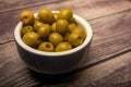 Green olives in a ceramic bowl on a wooden background . Close up Royalty Free Stock Photo