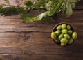 Green olives in a ceramic bowl on a wooden background.