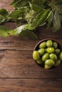 Green olives in a ceramic bowl on a wooden background.