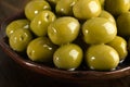 Green olives in oil stacked on a ceramic plate