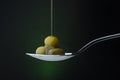 Green olives on a spoon on a dark background, stream of olive oil