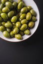 Green olives in a white bowl on a black background. Royalty Free Stock Photo