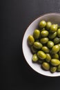 Green olives in a white bowl on a black background. Royalty Free Stock Photo