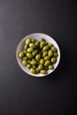 Green olives in a white bowl on a black background. Royalty Free Stock Photo