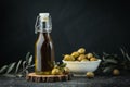 Green olives in a white bowl next to a bottle with olive oil and leaves on a black background. Bottle of cold pressed oil. Royalty Free Stock Photo