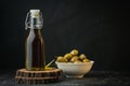 Green olives in a white bowl next to a bottle with olive oil and leaves on a black background. Bottle of cold pressed oil. Royalty Free Stock Photo