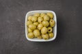 Green olives in a white ceramic bowl on a dark concrete background. Top view. close-up Royalty Free Stock Photo