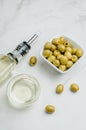 Green olives in a white ceramic bowl and glass bottle of olive oil on a white background. Top view Royalty Free Stock Photo