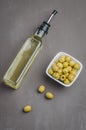 Green olives in a white ceramic bowl and glass bottle of olive oil on a dark background. Top view Royalty Free Stock Photo