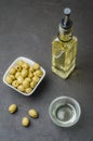 Green olives in a white ceramic bowl and glass bottle of olive oil on a dark background. Top view Royalty Free Stock Photo