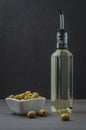 Green olives in a white ceramic bowl and glass bottle of olive oil on a dark stone background. Selective focus. Organic olive oil Royalty Free Stock Photo