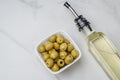 Green olives in a white ceramic bowl and glass bottle of olive oil on a light concrete background. Top view Royalty Free Stock Photo