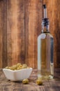 Green olives in a white ceramic bowl and glass bottle of olive oil on a wooden background. Selective focus. Organic olive oil Royalty Free Stock Photo