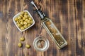 Green olives in a white ceramic bowl and glass bottle of olive oil on a wooden background. Top view Royalty Free Stock Photo