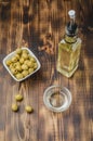 Green olives in a white ceramic bowl and glass bottle of olive oil on a wooden background. Top view Royalty Free Stock Photo