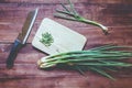 Green onions with Knife on chopping board on wooden Royalty Free Stock Photo