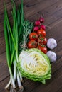 Green onions, yellow peppers, cherry tomatoes, garlic and cabbage on dark wooden table. Top views, close-up Royalty Free Stock Photo