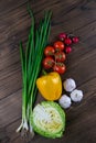 Green onions, yellow peppers, cherry tomatoes, slot and cabbage on dark wooden table. Top views, close-up Royalty Free Stock Photo